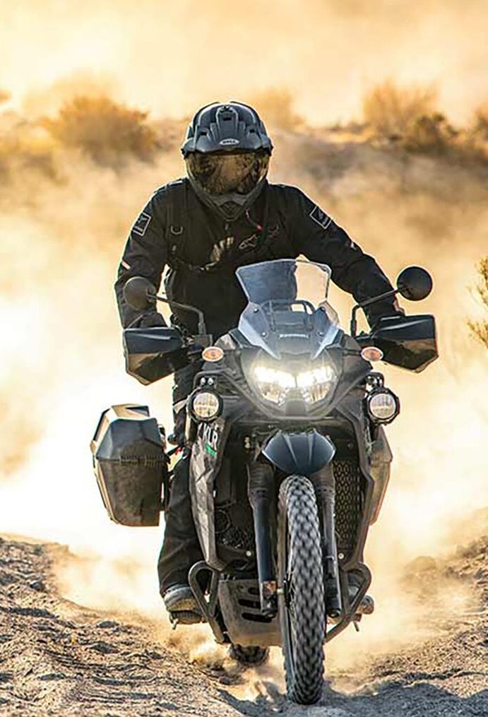 Two dirt bikes racing across a desert track, clouds of dust in their tracks.