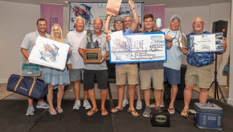 Team Wolverine standing at an awards ceremony holding their prized check, trophies and other awards.